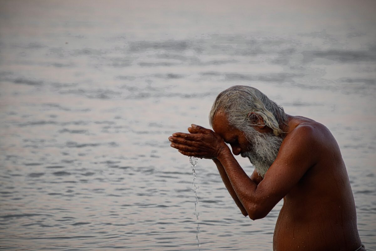 A devotee offering morning prayers in the holy Ganga river at the triveni ghat, Rishikesh