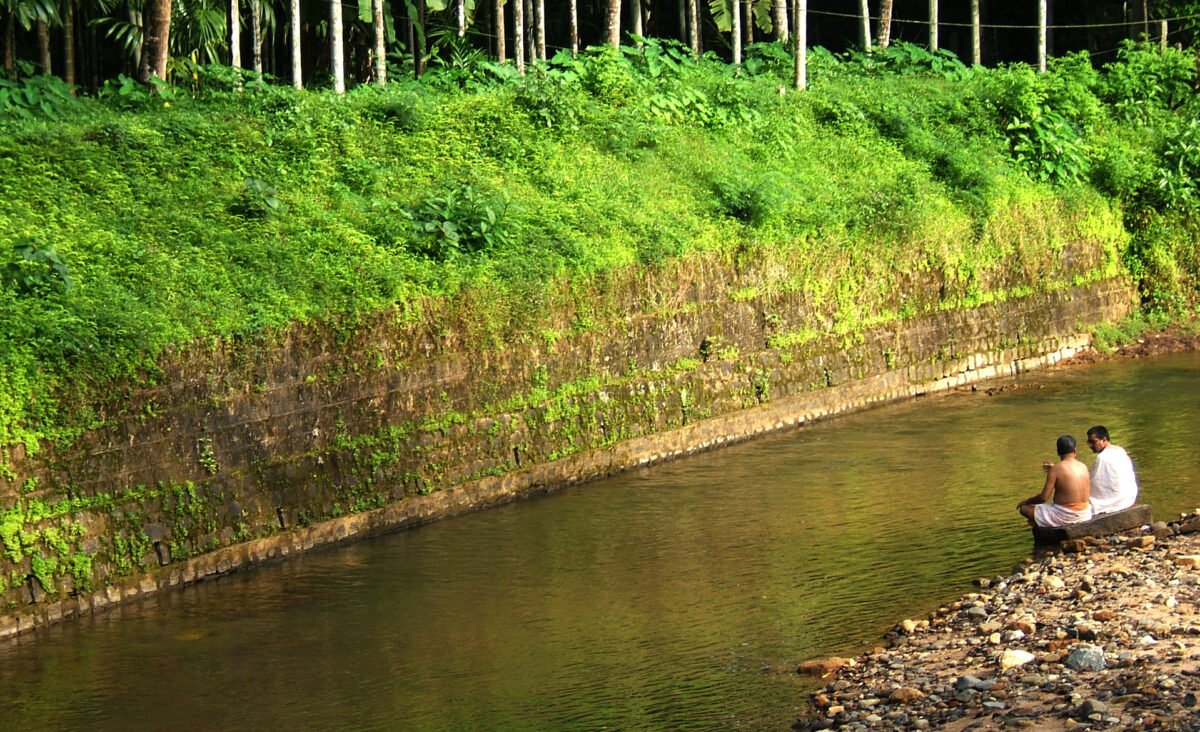 Dos hombres hindúes aprecian el ambiente sereno de un arroyo en Kerala